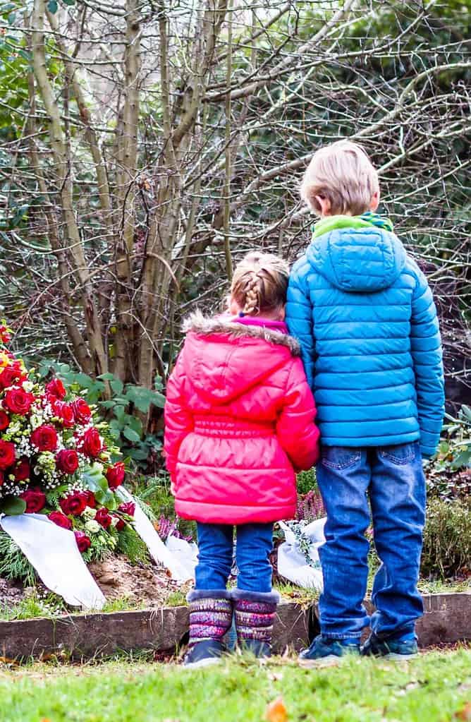 Twee rouwende kinderen voor een graf.