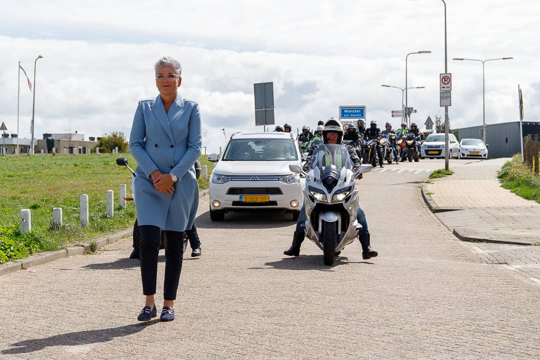 Een vrouw in een blauwe jas staat naast motorfietsen.