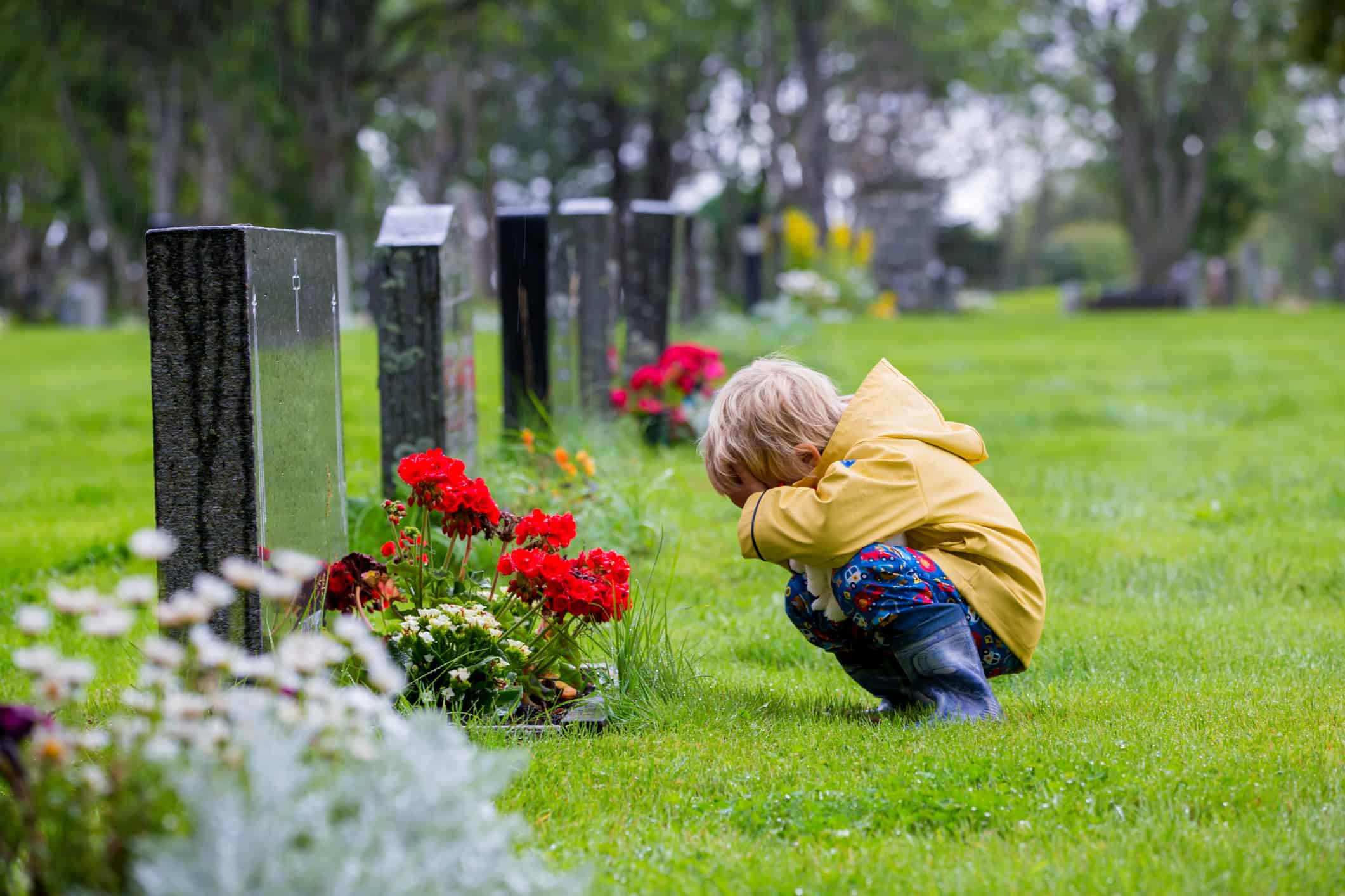 Een kleine jongen die het concept van verlies omarmt terwijl hij voor een kerkhof knielt.