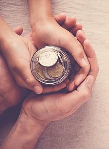 Twee handen die een pot met munten vasthouden die tarieven (tarieven) illustreren.