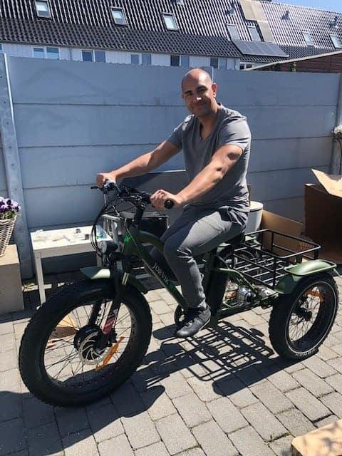 Ricardo Mooij, een man zittend op een fiets met een aanhanger eraan.